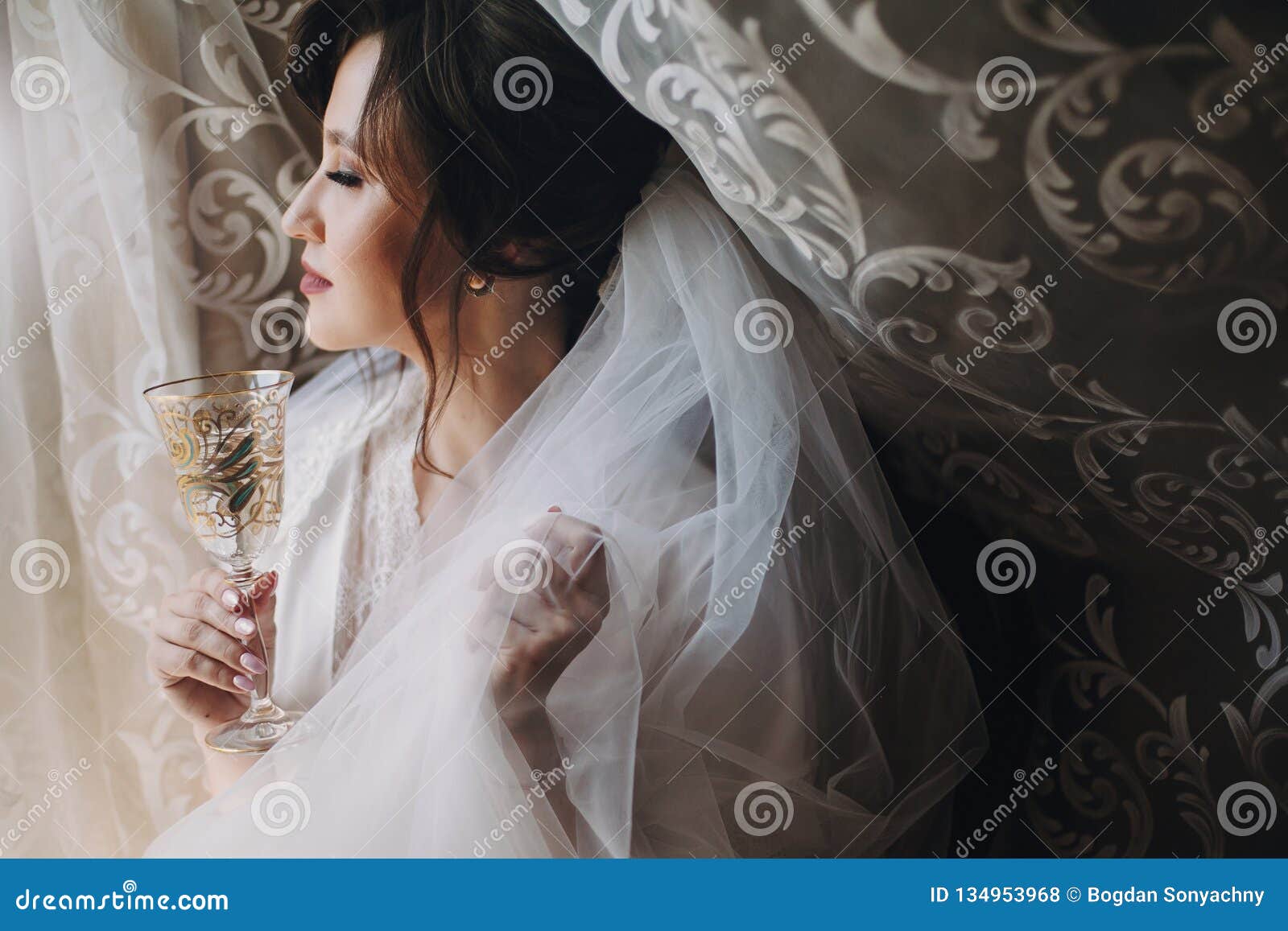 Beautiful Stylish Brunette Bride Posing In Silk Robe Under Veil With