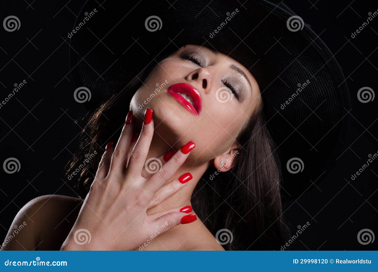 Beautiful, stylish woman in hat, posing seductivel. A beautiful, stylish and woman, posing seductively in a stylish hat with bright red nails and lips
