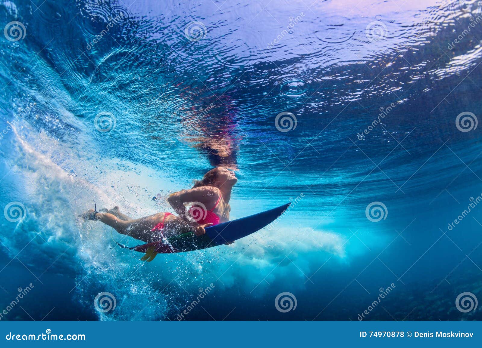 beautiful surfer girl diving under water with surf board