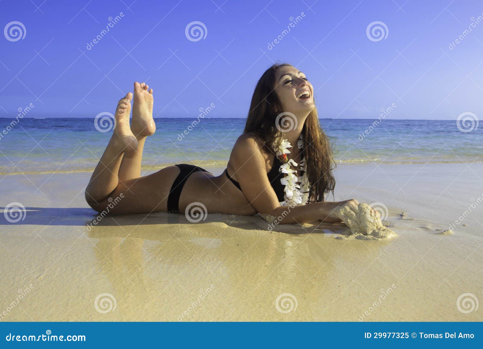 Outdoor shot of smiling young female model girl in bikini lying