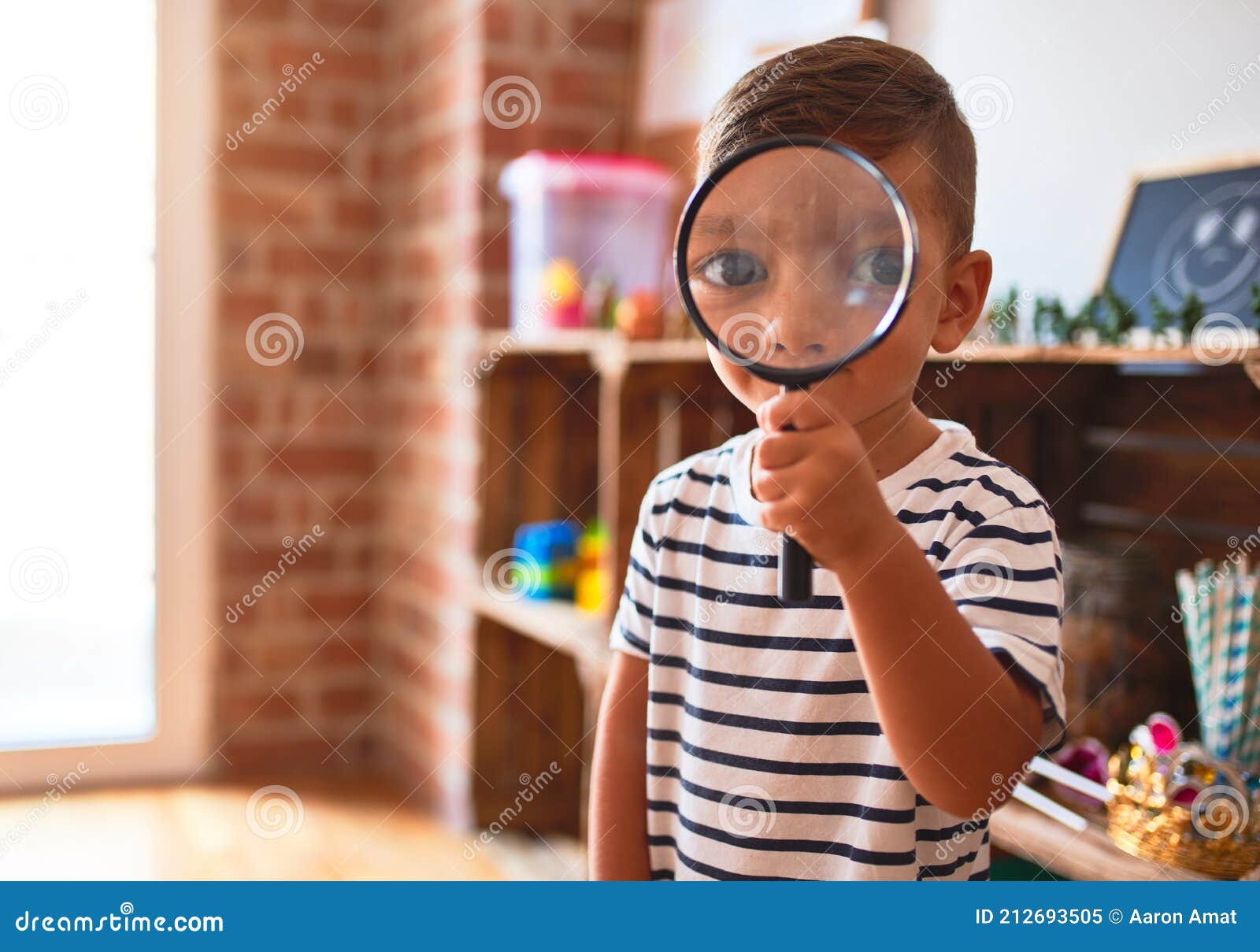 Beautiful Toddler Boy Using Magnifying Glass at Kindergarten Stock