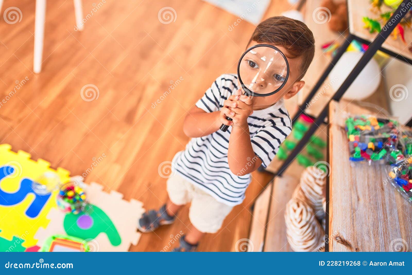 Beautiful Toddler Boy Using Magnifying Glass at Kindergarten Stock