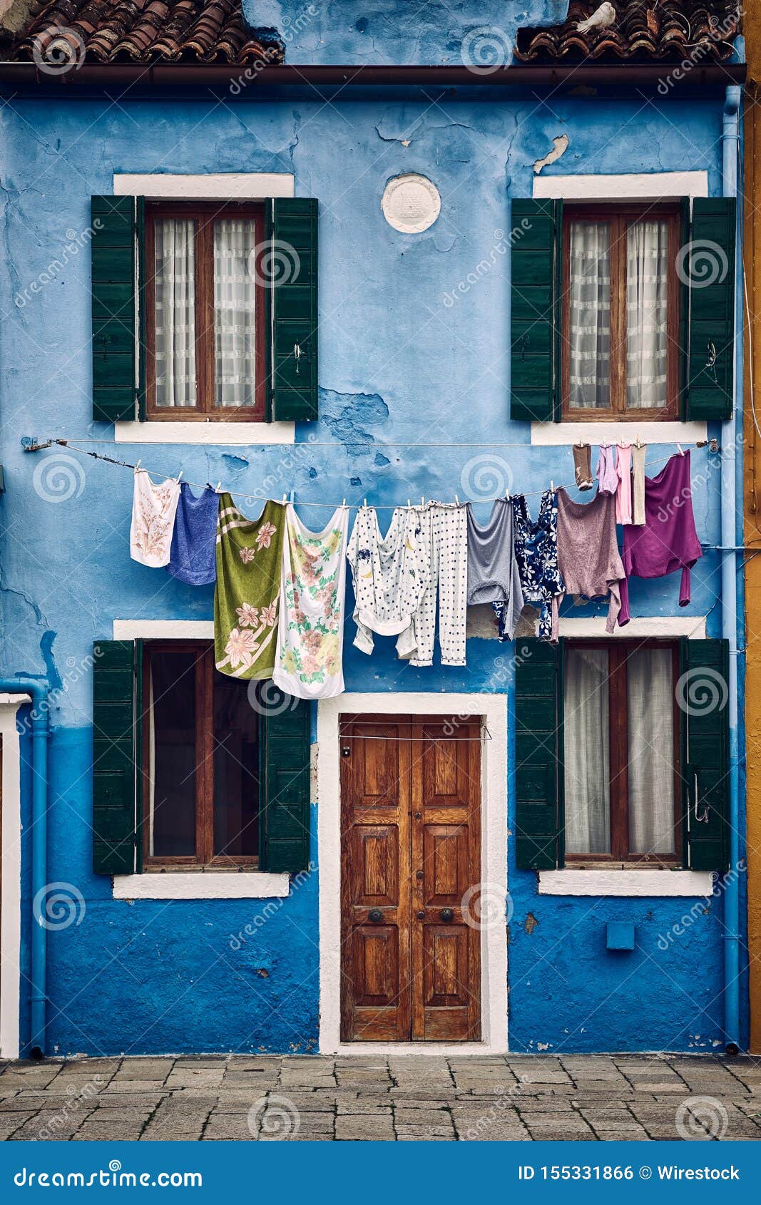A beautiful vertical symmetric shot of a suburban blue building with clothes hanging on a rope