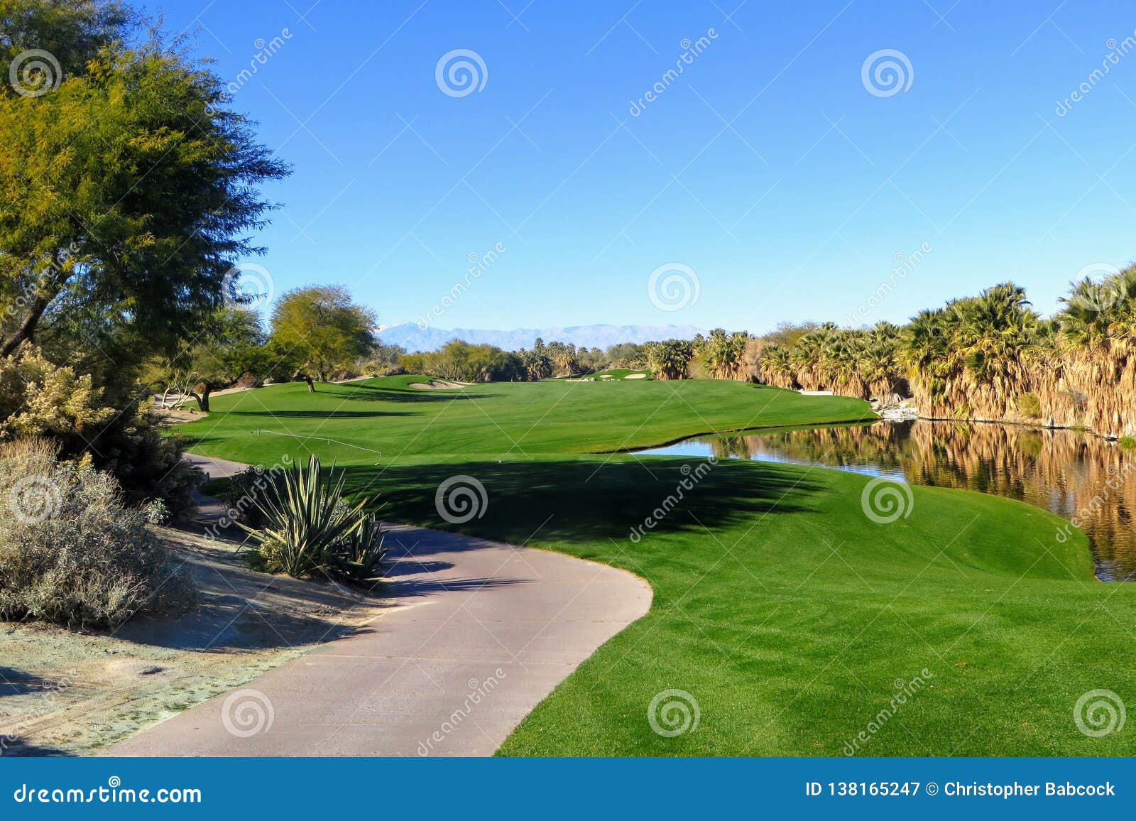 a beautiful view of a par 5 with the desert surrounding the hole as well as a pond. the golf course is in palm springs