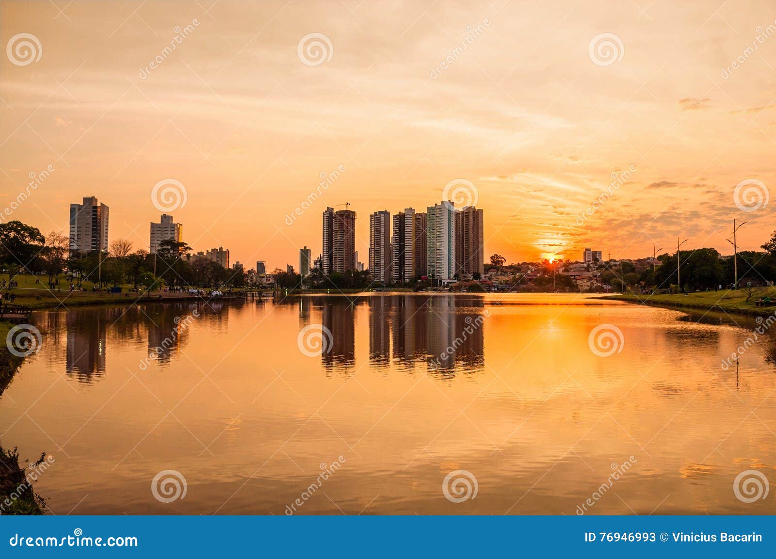 a beautiful warm sunset at the lake with buildings and the city background. scene reflected on water.