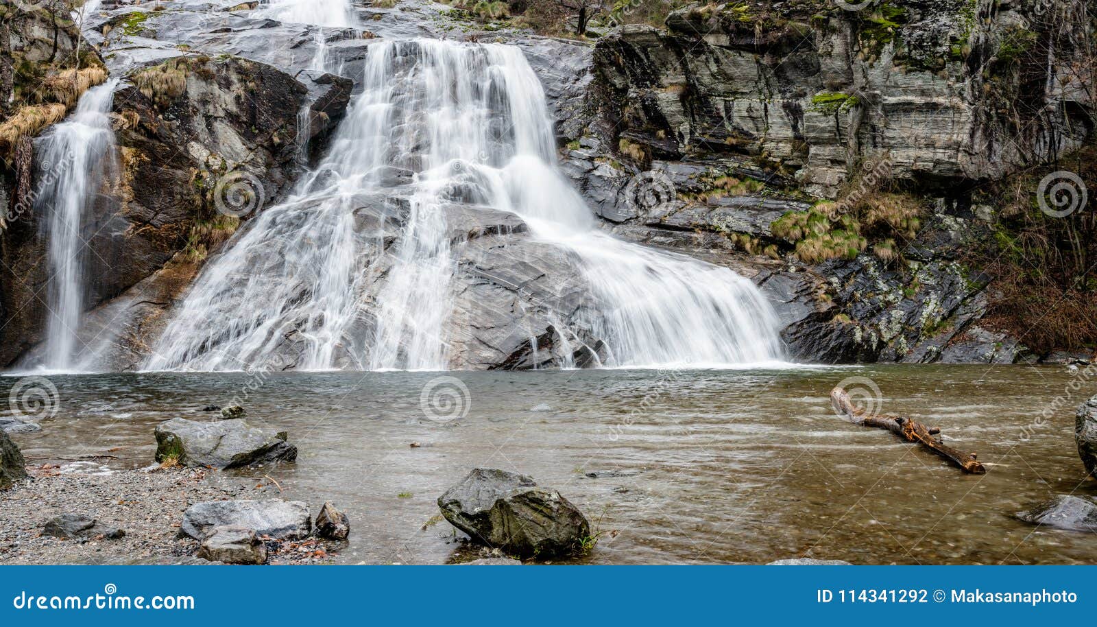 beautiful wide waterfall with a swimming hole in the foreground in the early morning in southern switzerland