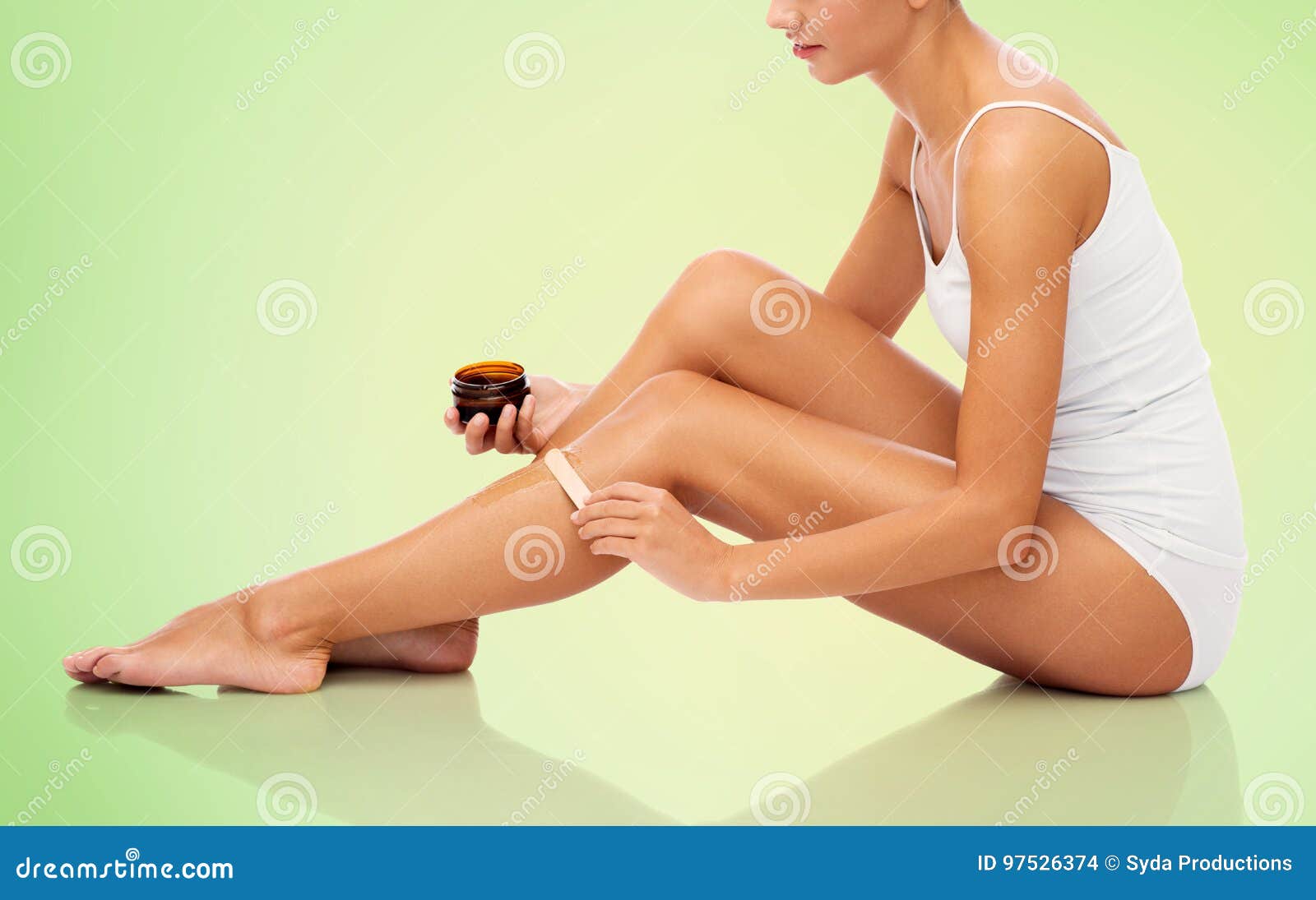 beautiful woman applying depilatory wax to her leg