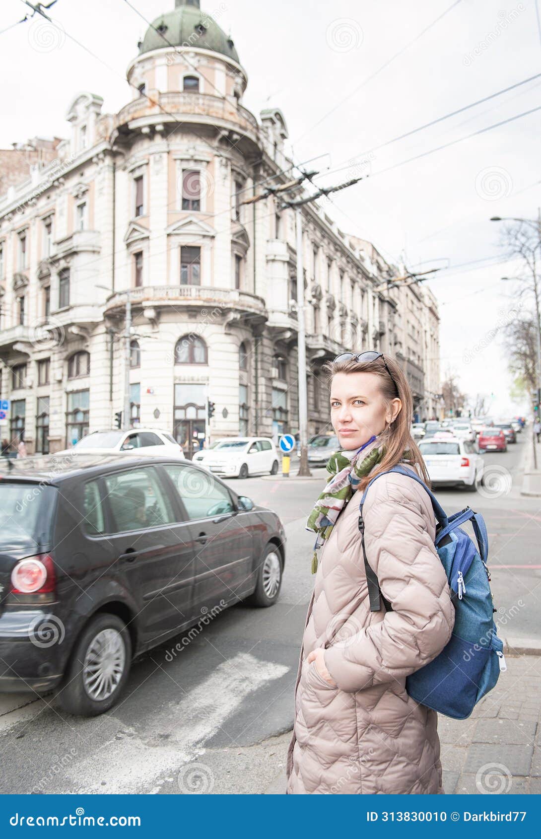beautiful woman with bagpack and sunglasses standing on the street in the belgrade city, serbia
