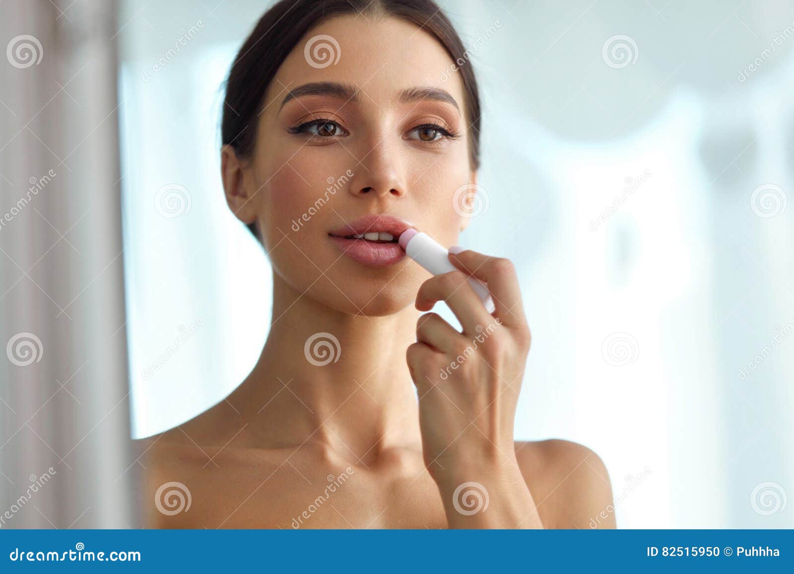 beautiful woman with beauty face applies balm on lips. skin care