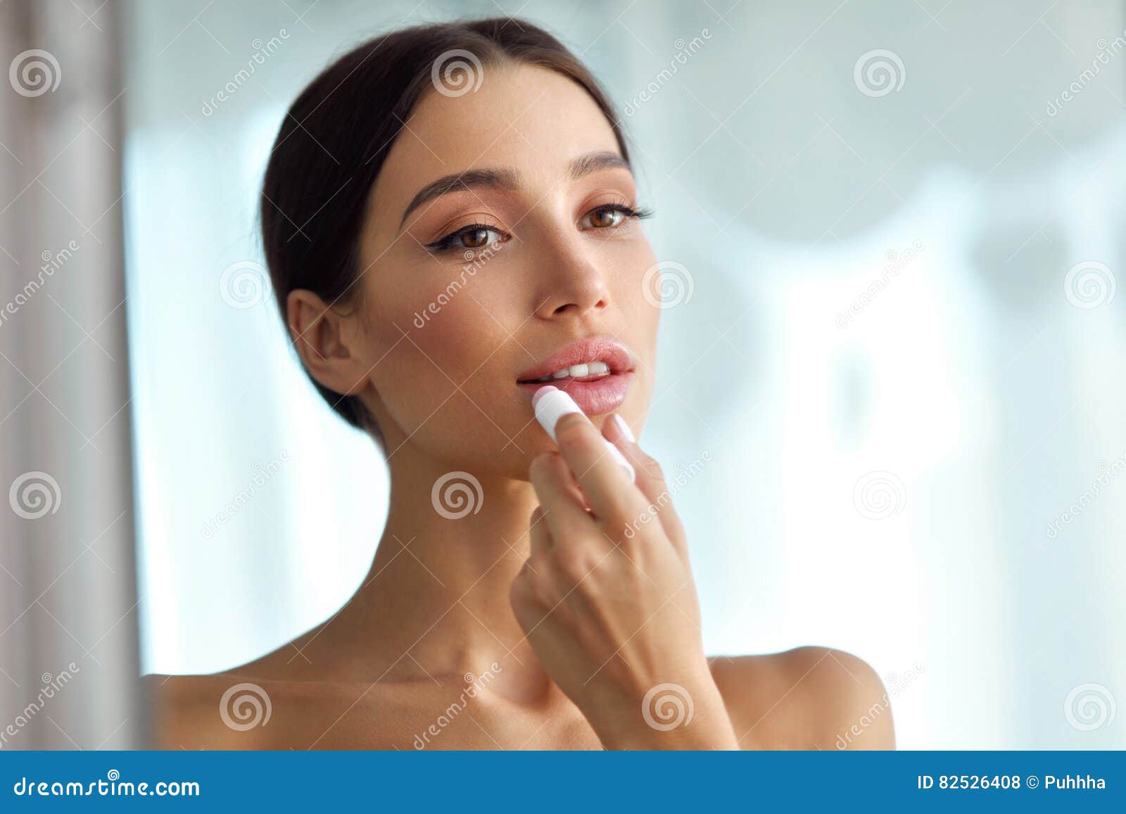 beautiful woman with beauty face applies balm on lips. skin care