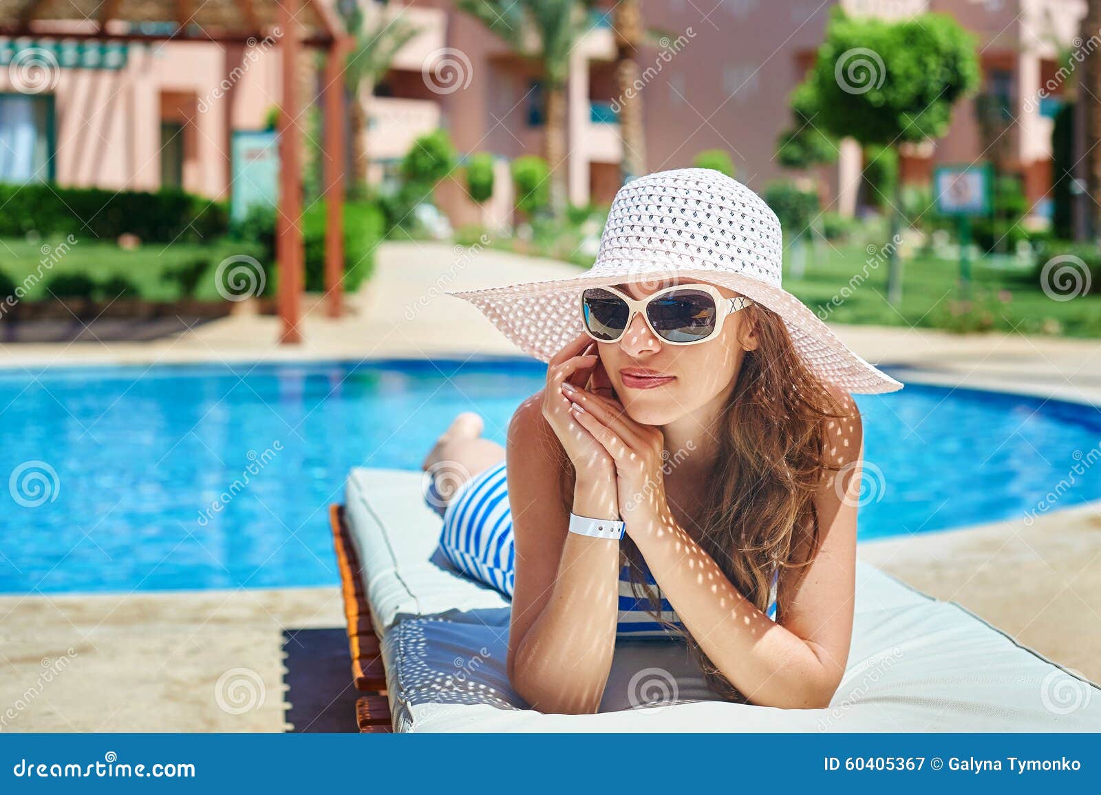 Beautiful Woman In A Big White Hat On A Lounger By The Pool Stock Image