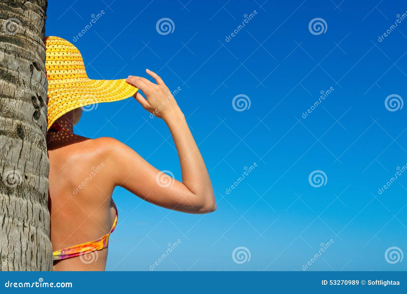 beautiful woman in bikini and sunhat standing with hands raised