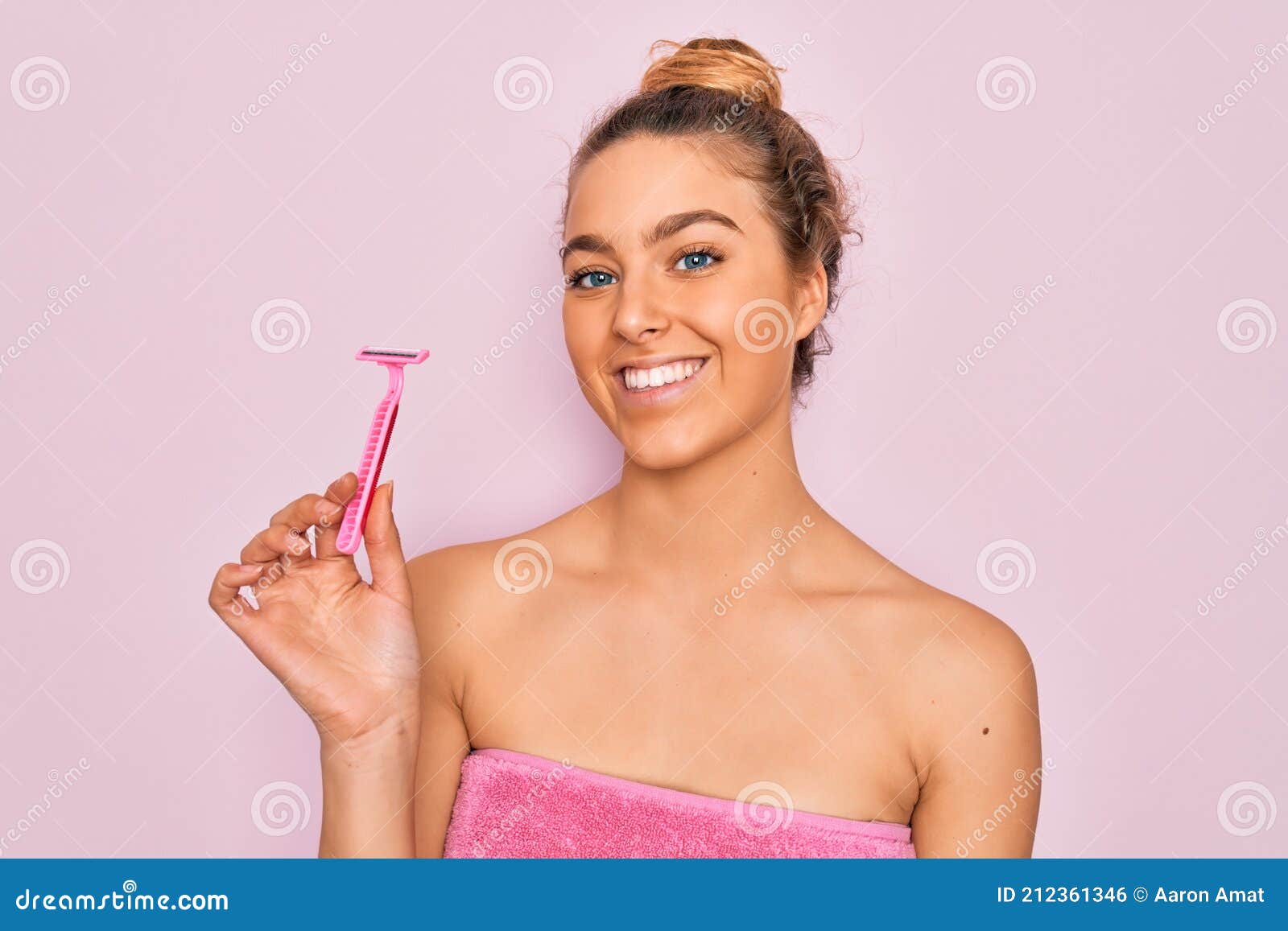 beautiful woman with blue eyes wearing towel shower after bath holding depilation razon with a happy face standing and smiling