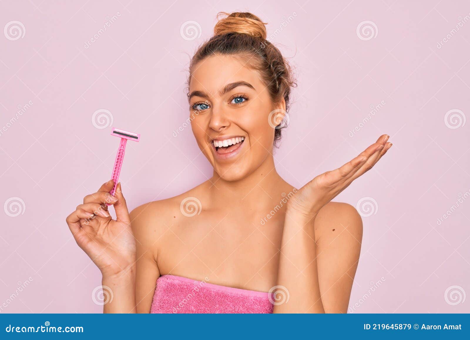 beautiful woman with blue eyes wearing towel shower after bath holding depilation razon very happy and excited, winner expression