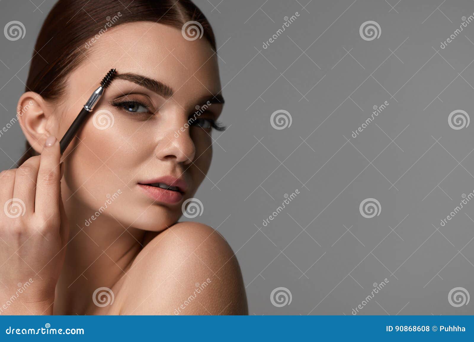 beautiful woman brushing eyebrows with brow tool