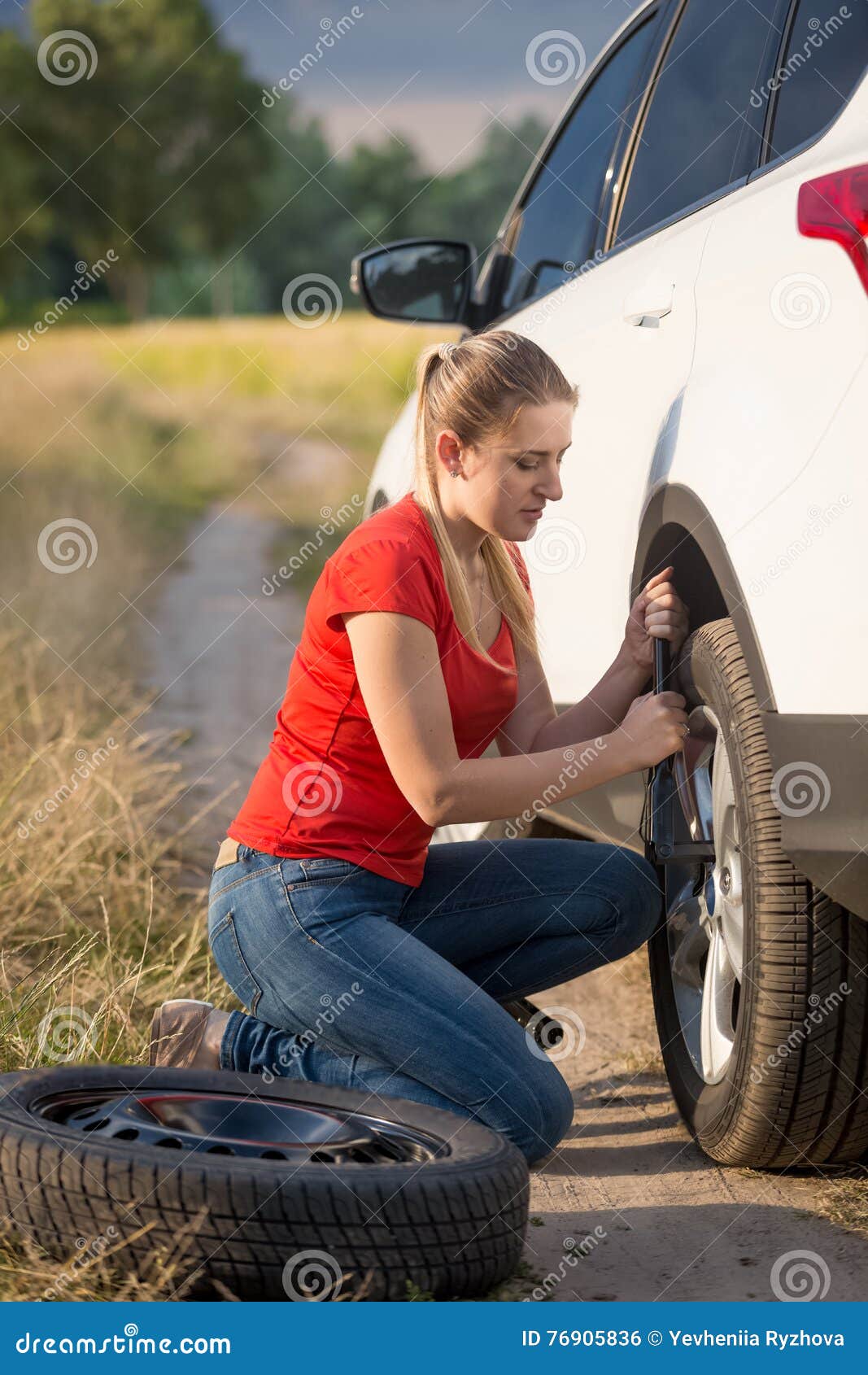 Beautiful Woman Changing Flat Tire on the Rural Road Stock Photo