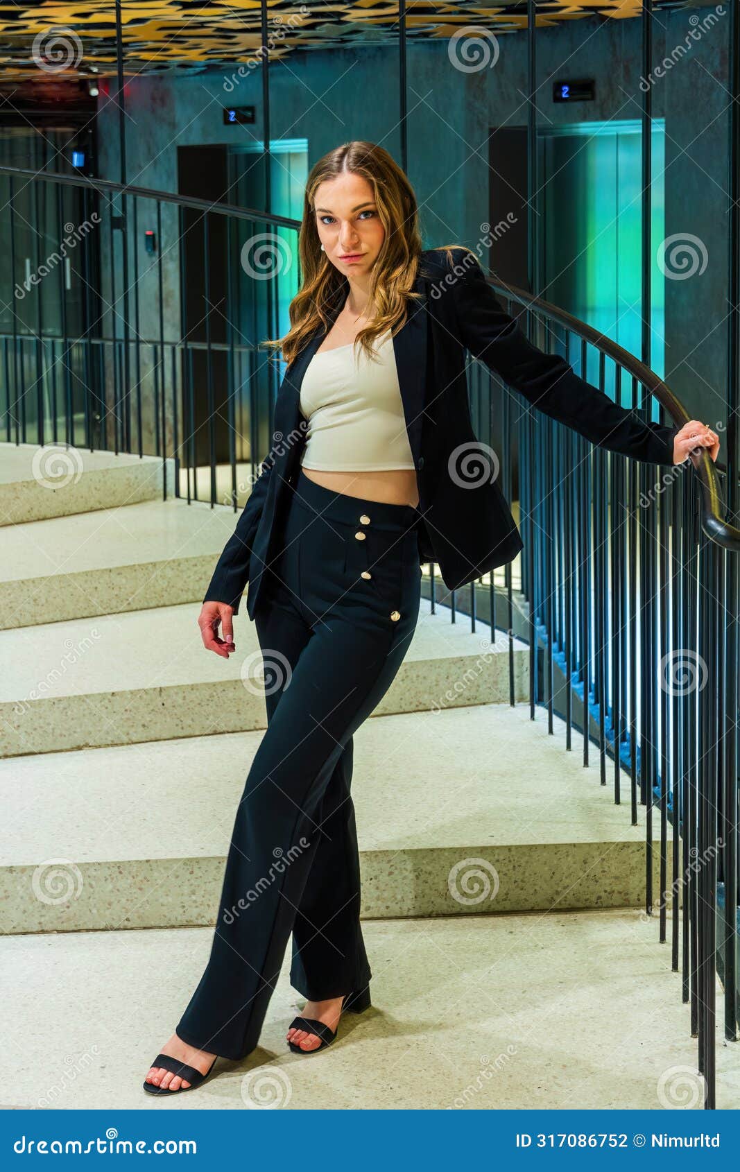 beautiful woman in classic suit on spiral staircase holding bannister