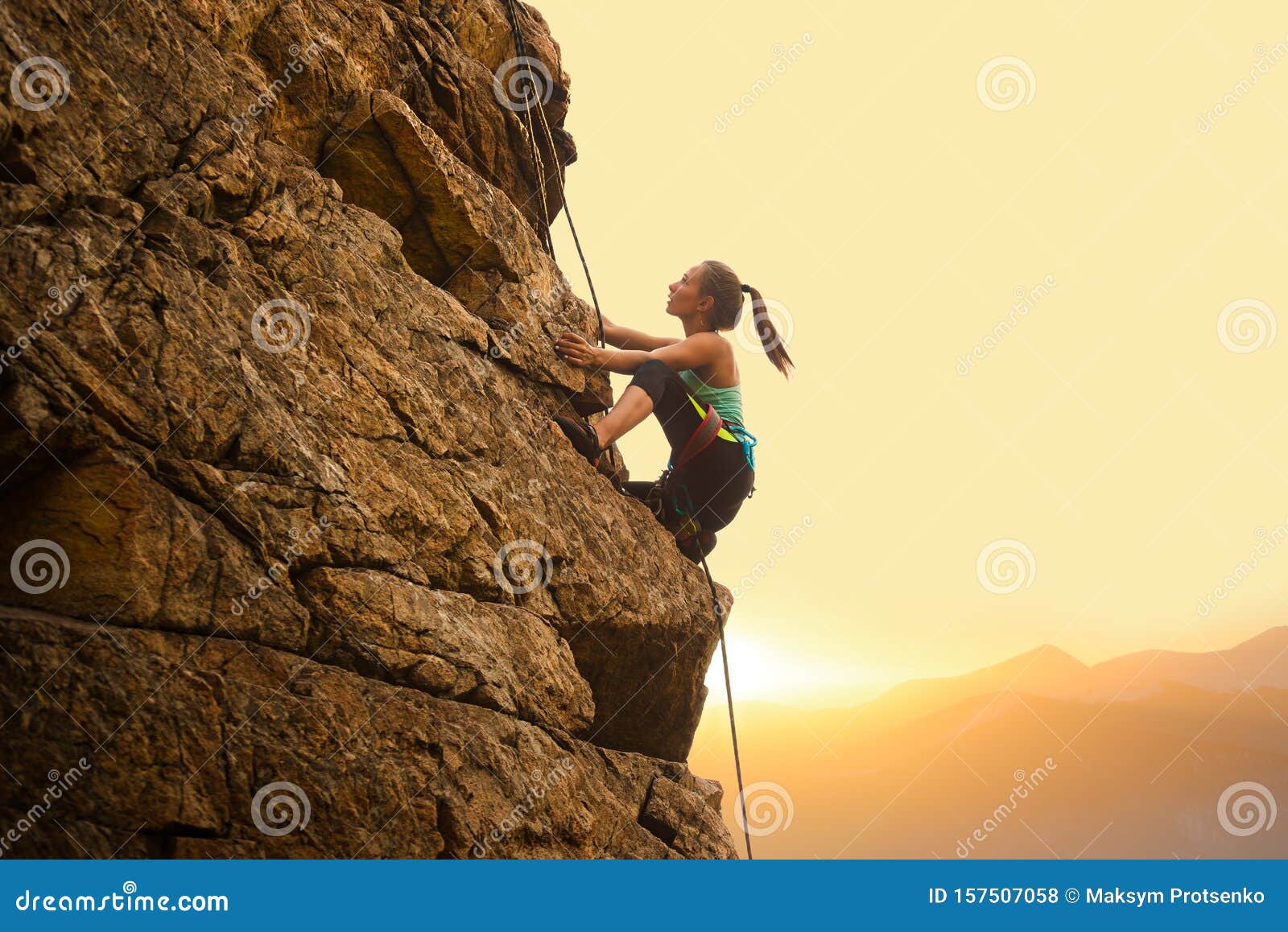beautiful woman climbing on the rock at foggy sunset in the mountains. adventure and extreme sport concept