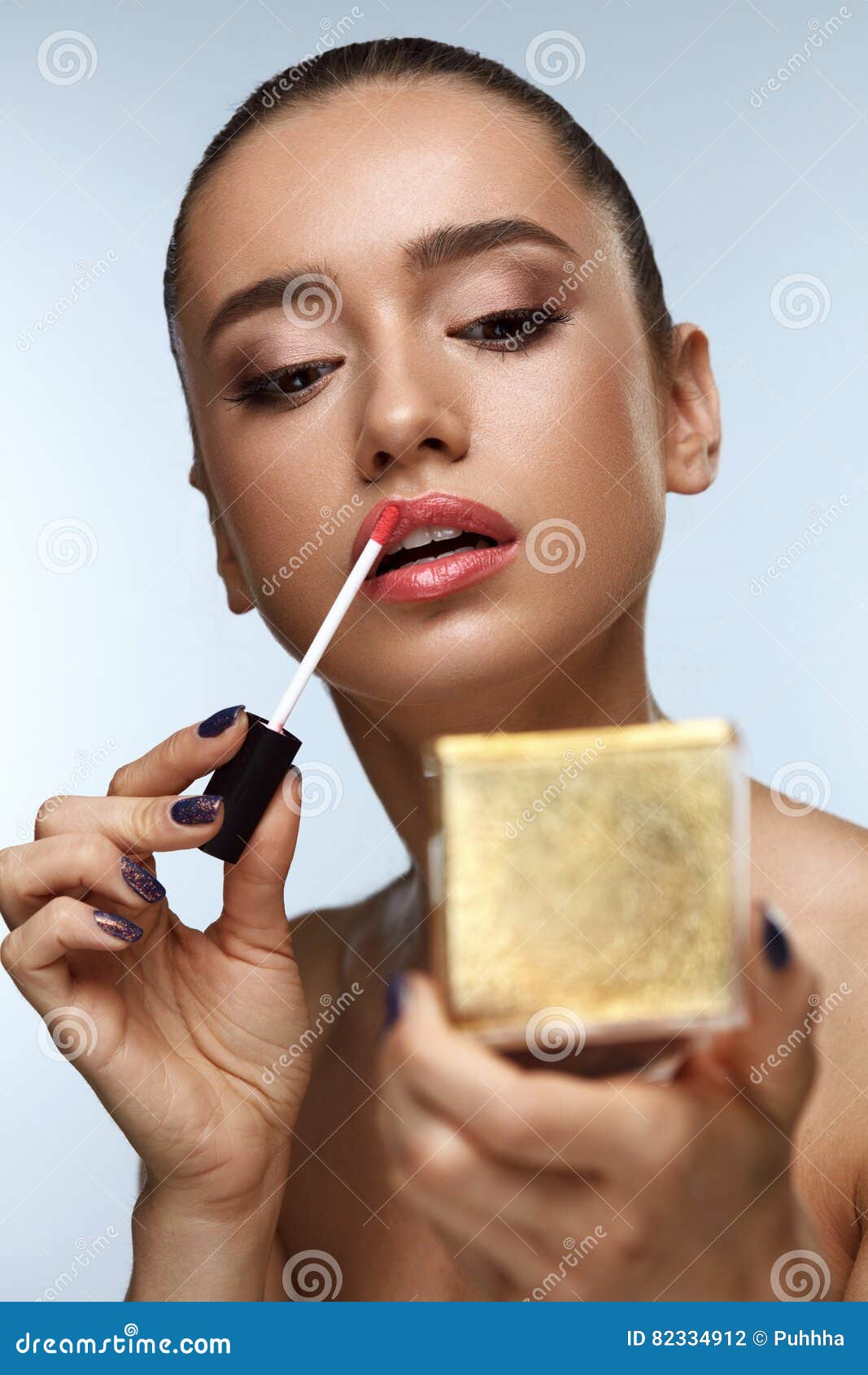 beautiful woman doing makeup putting lipgloss on lips. cosmetics