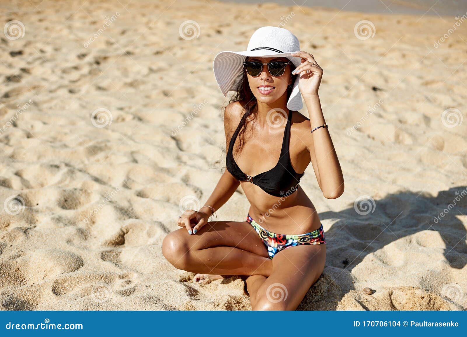 beautiful woman in hat and sunglasses enjoing summer on a beach