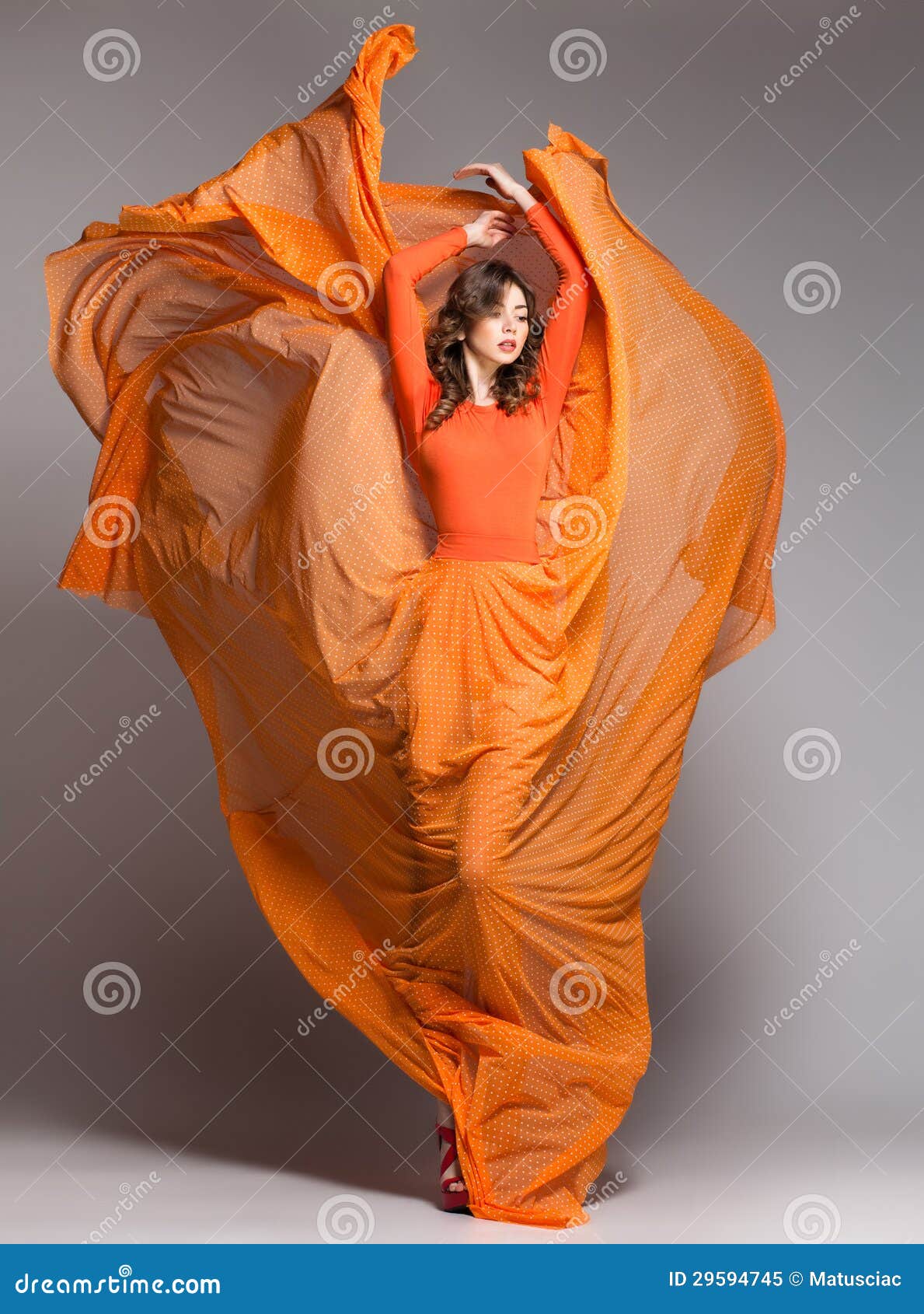 beautiful woman in long orange dress posing dramatic