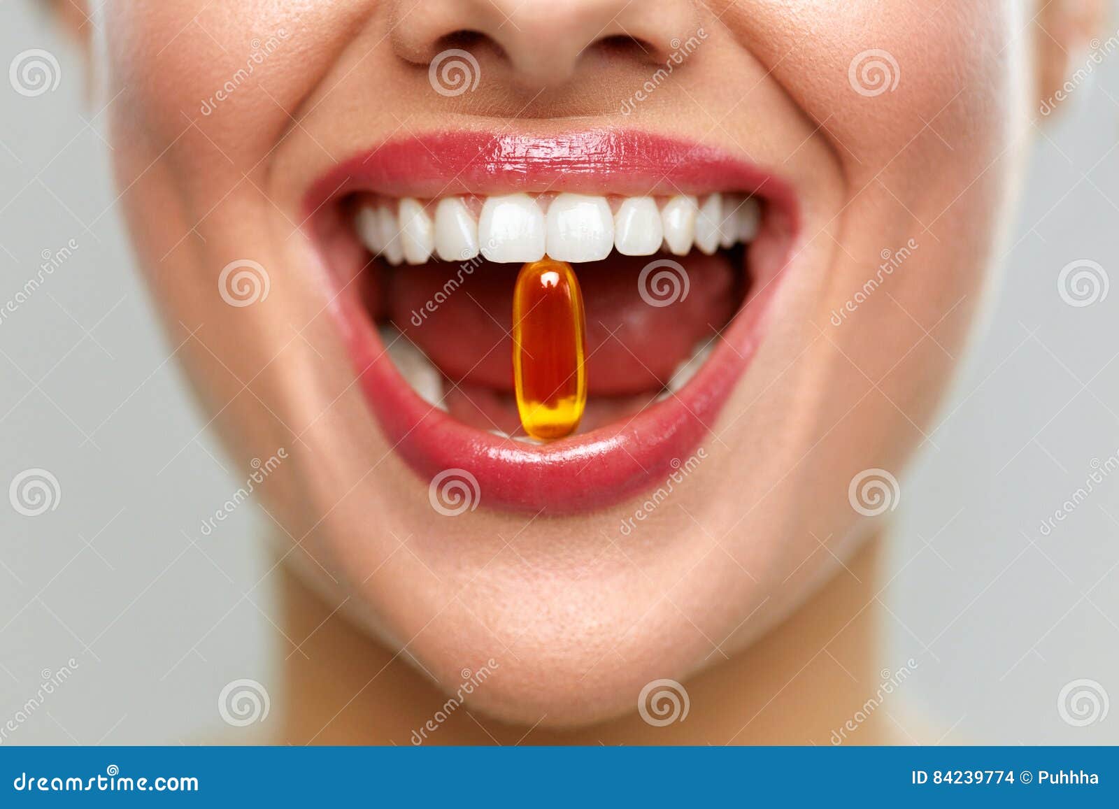 beautiful woman mouth with pill in teeth. girl taking vitamins