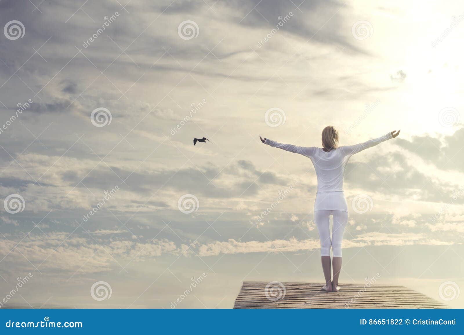 beautiful woman with open arms meditating in front of a spectacular sky