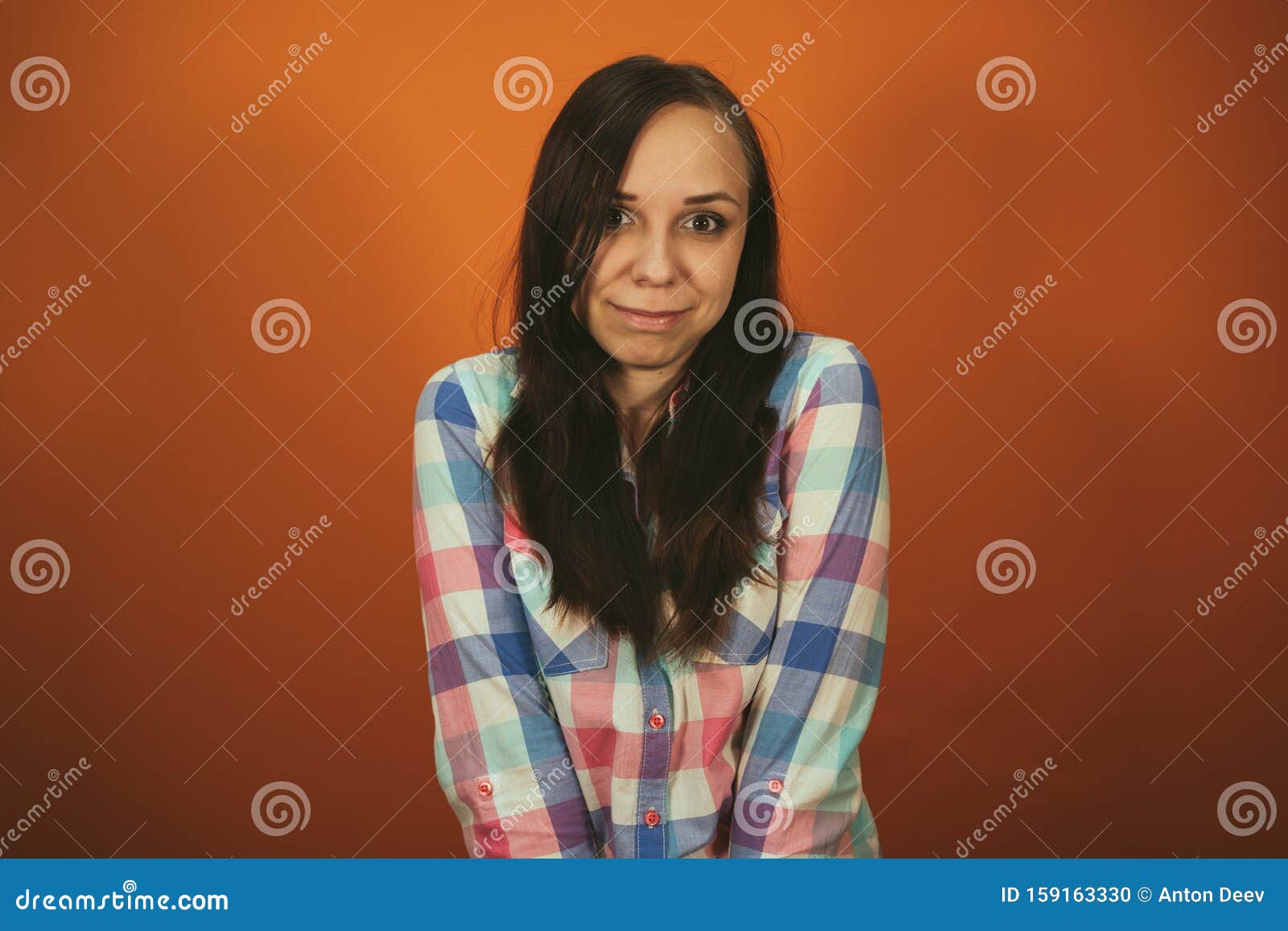 A Beautiful Woman In A Plaid Shirt Poses On An Orange Background Stock