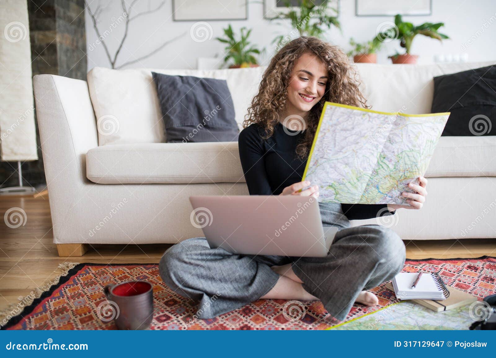 beautiful woman planning summer vacation abroad, going on trip alone. sitting on floor, working on itinerary on laptop