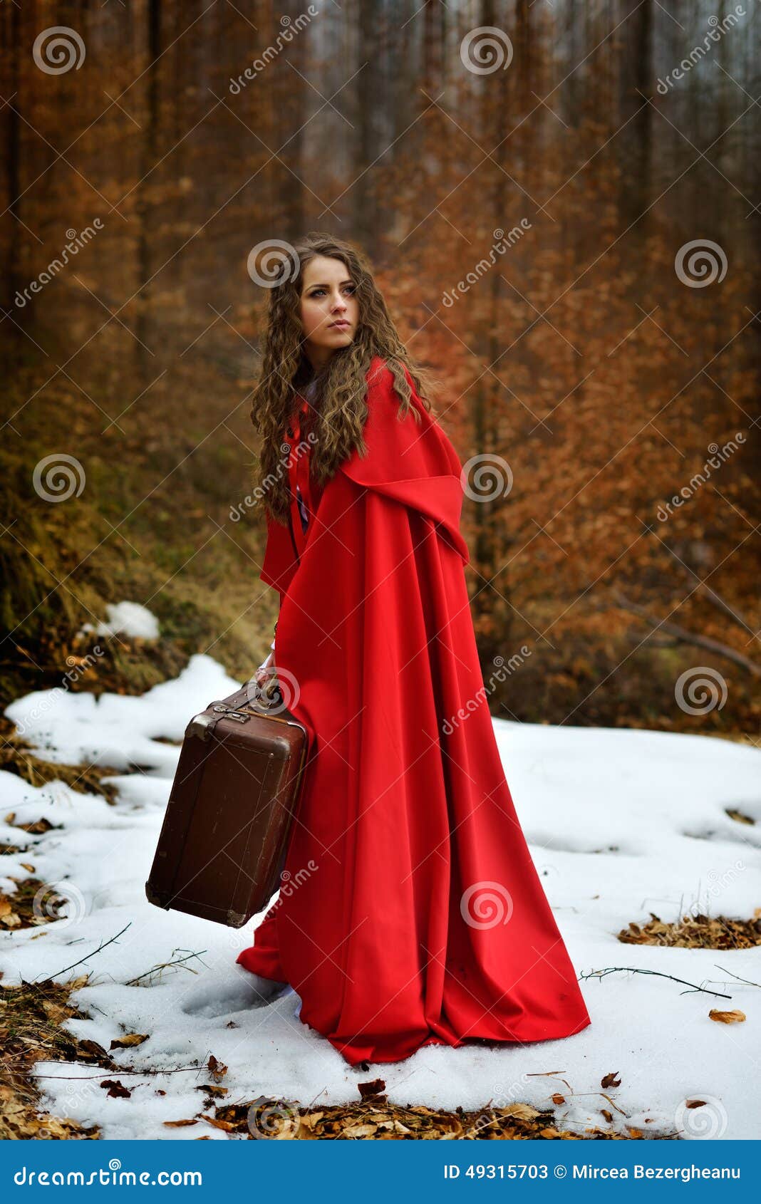 beautiful woman with red cloak and suitcase alone in the woods