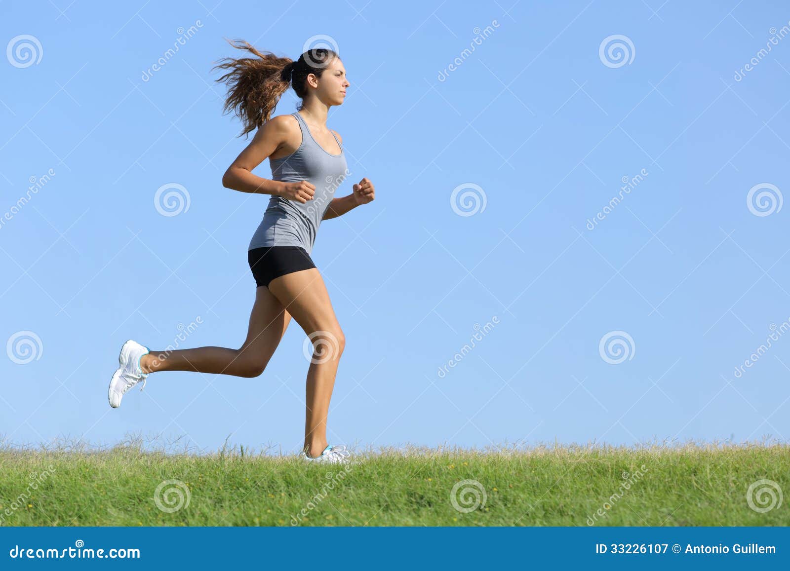 Fit Beautiful Young Woman Running In The Park. She Is Wearing