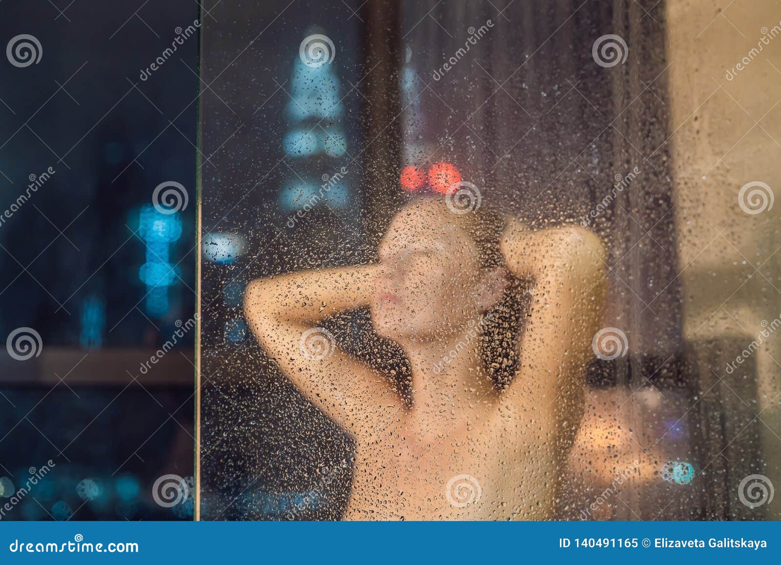 Beautiful Woman In The Shower Behind Glass With Drops On The Background
