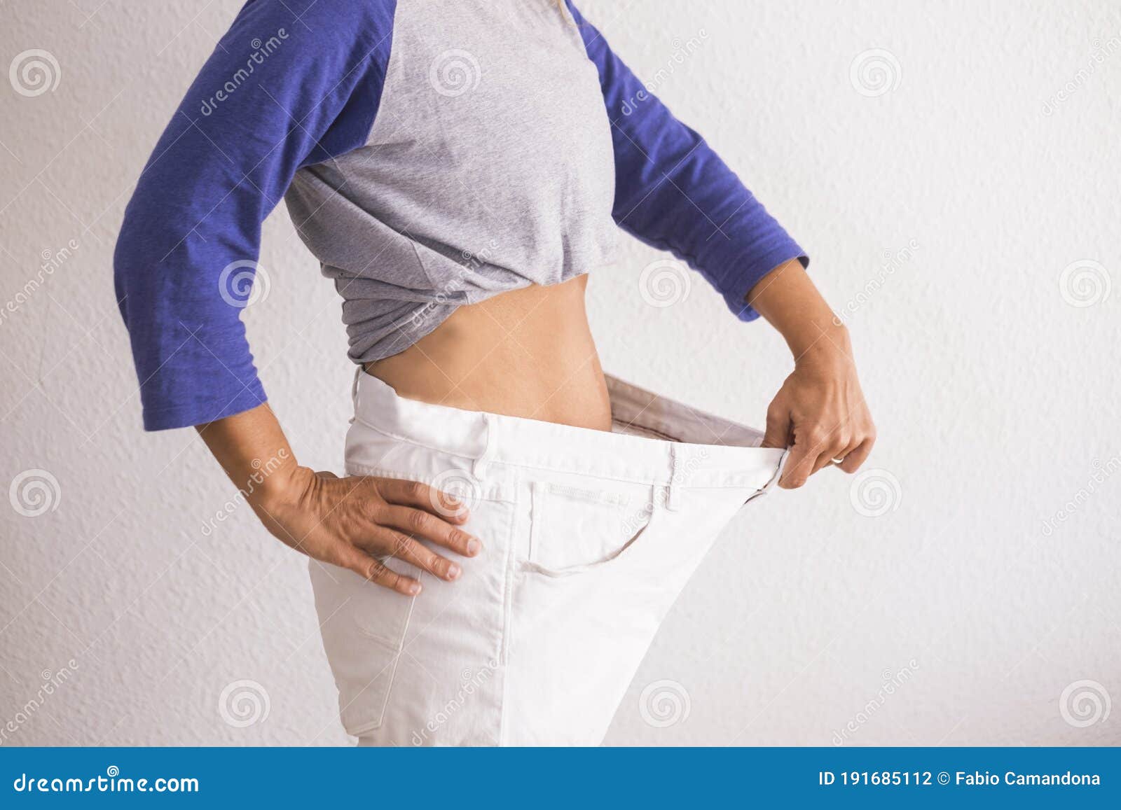 beautiful woman showing her old big pantalon after losing weight ah home - fitness at home and working to stay better with