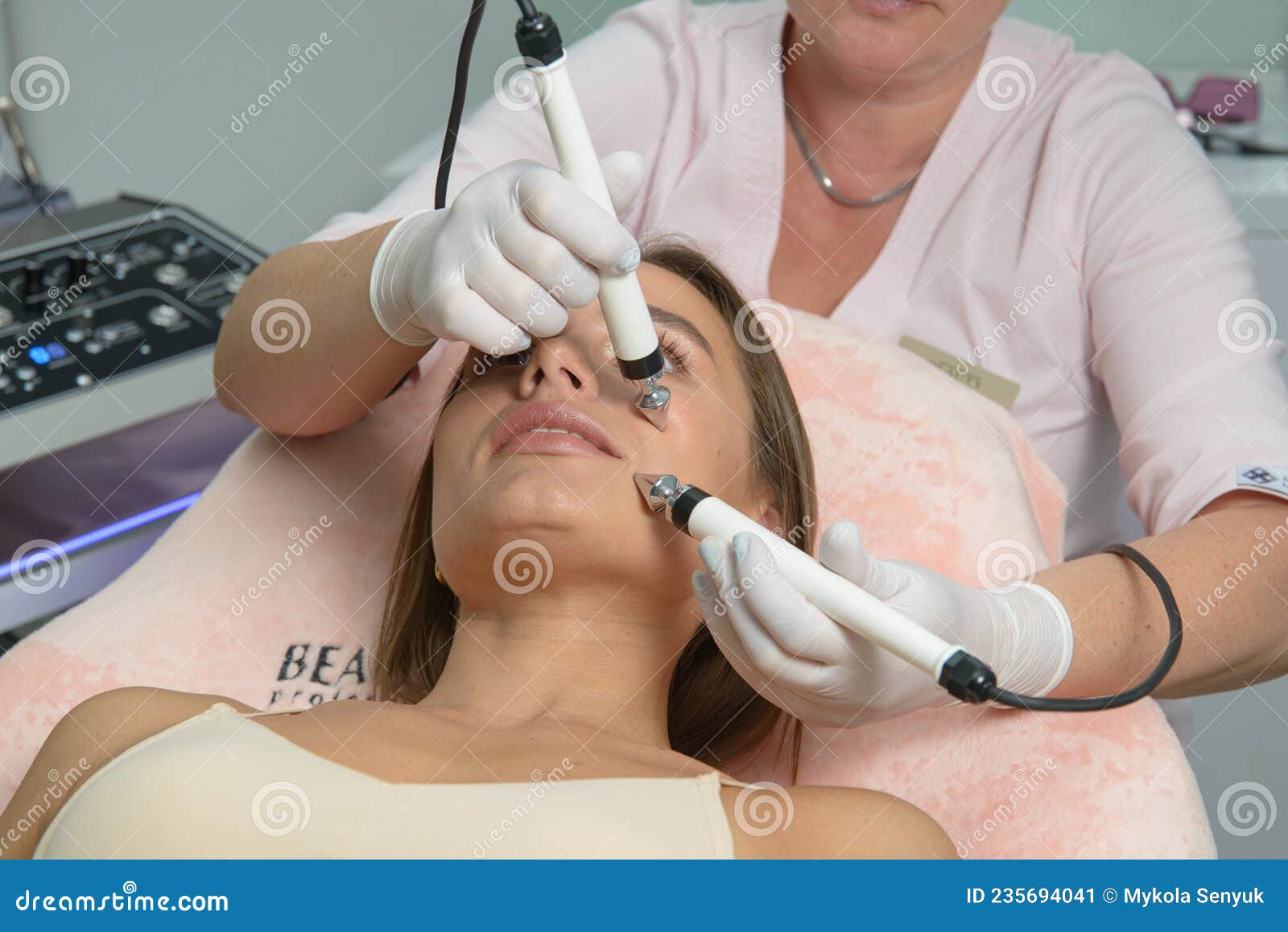 Beautiful Woman At Spa Clinic Receiving Stimulating Electric Facial Treatment From Therapist