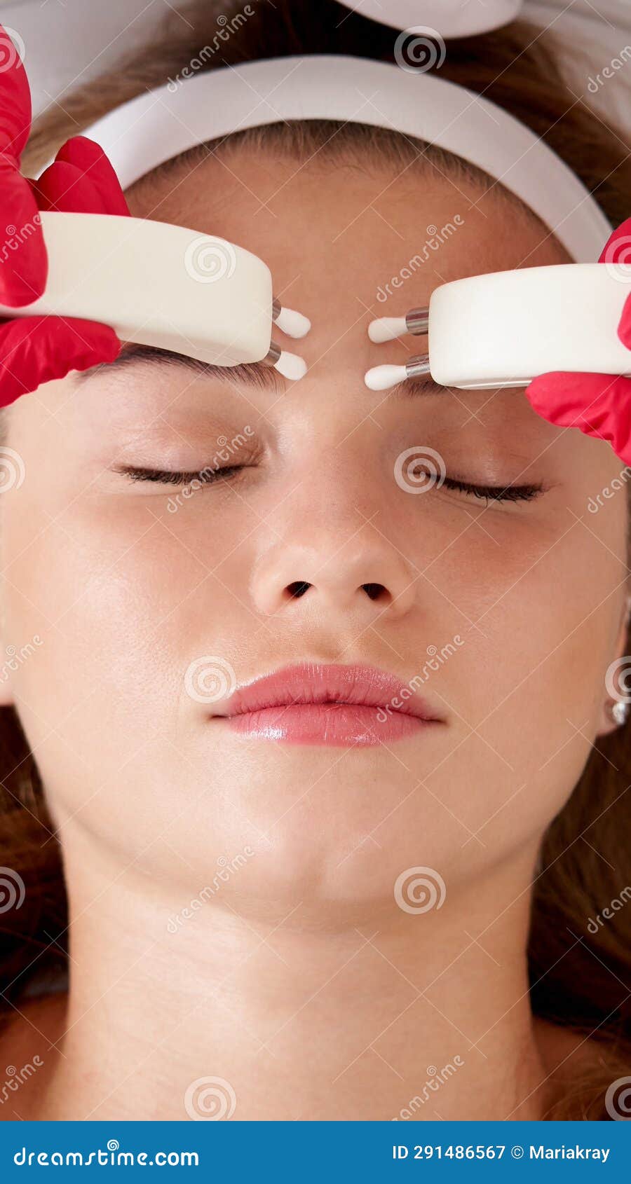 Beautiful Woman In Spa Clinic Receiving Stimulating Electric Facial Treatment From Therapist