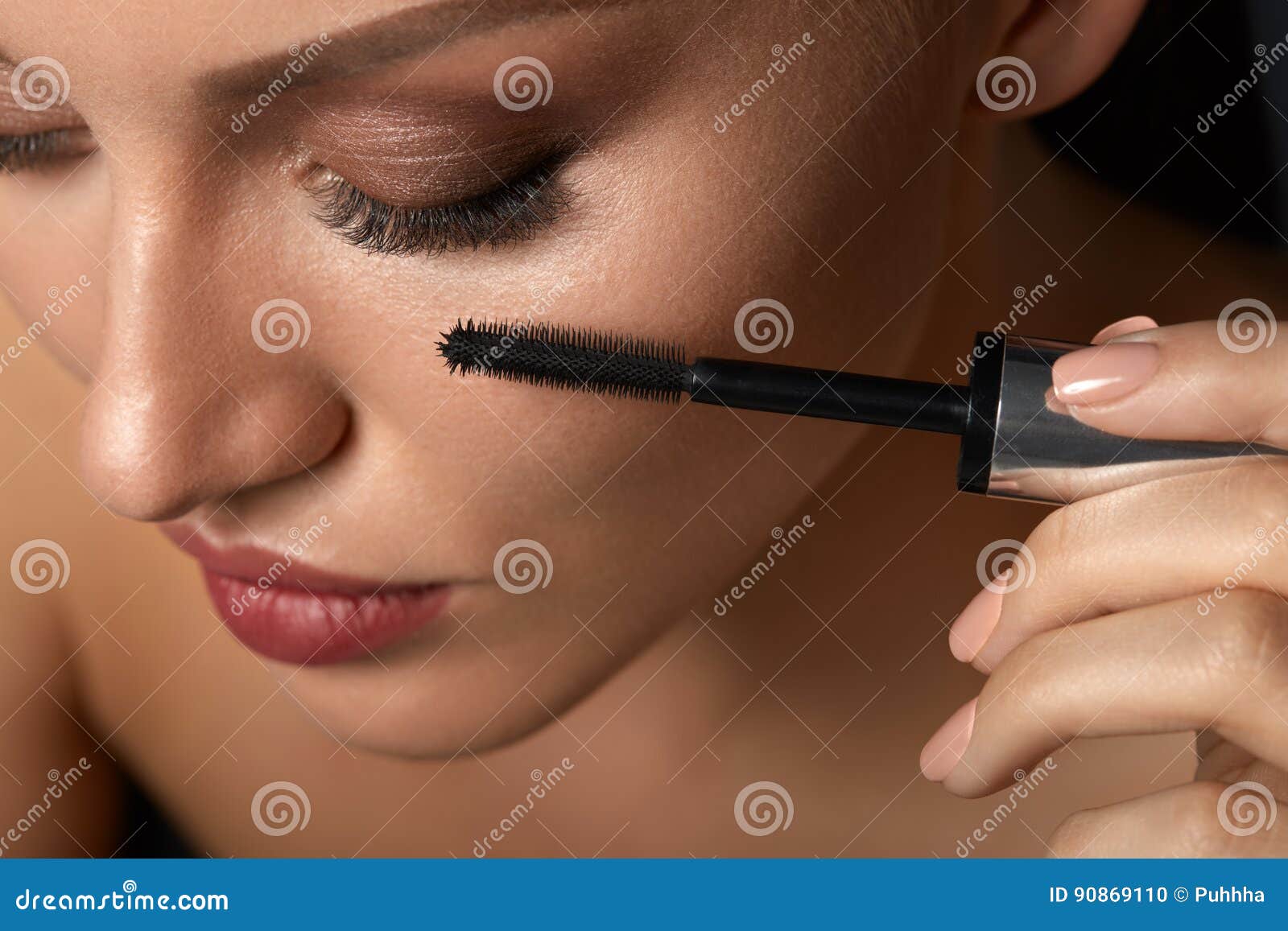 beautiful woman using black mascara on closed eyes