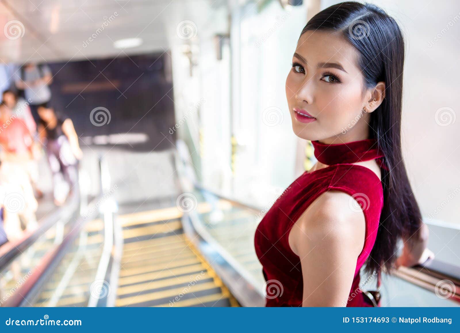 Beautiful Young Asian Woman In Red Dress Going Down The Escalator In