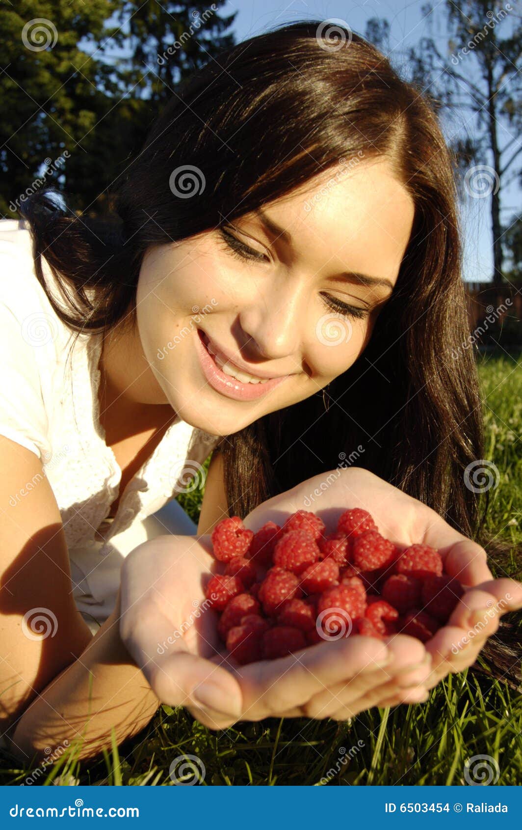 beautiful young brunet girl holding raspberries