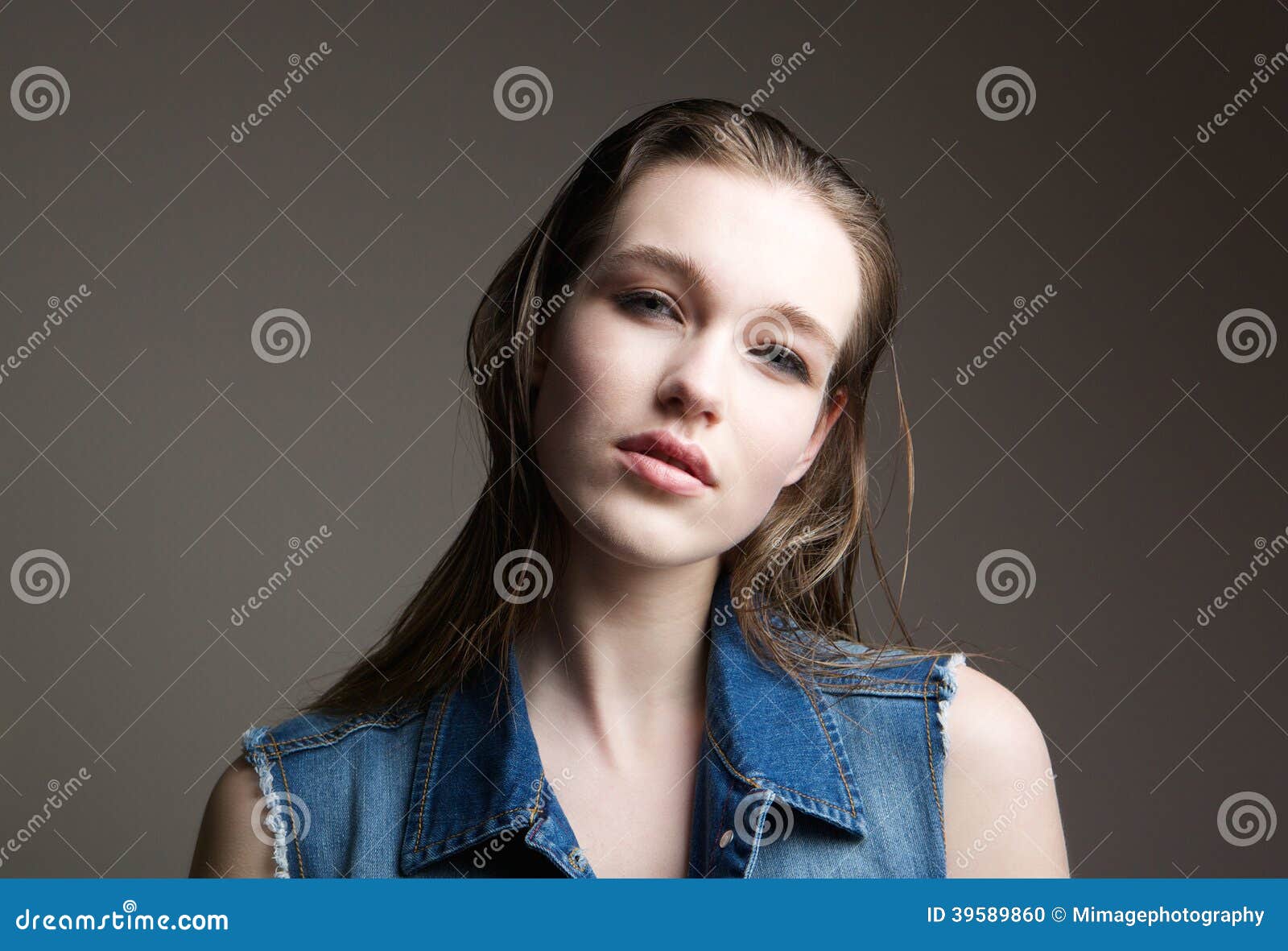 Close up portrait of a beautiful young brunette fashion model posing on gray background