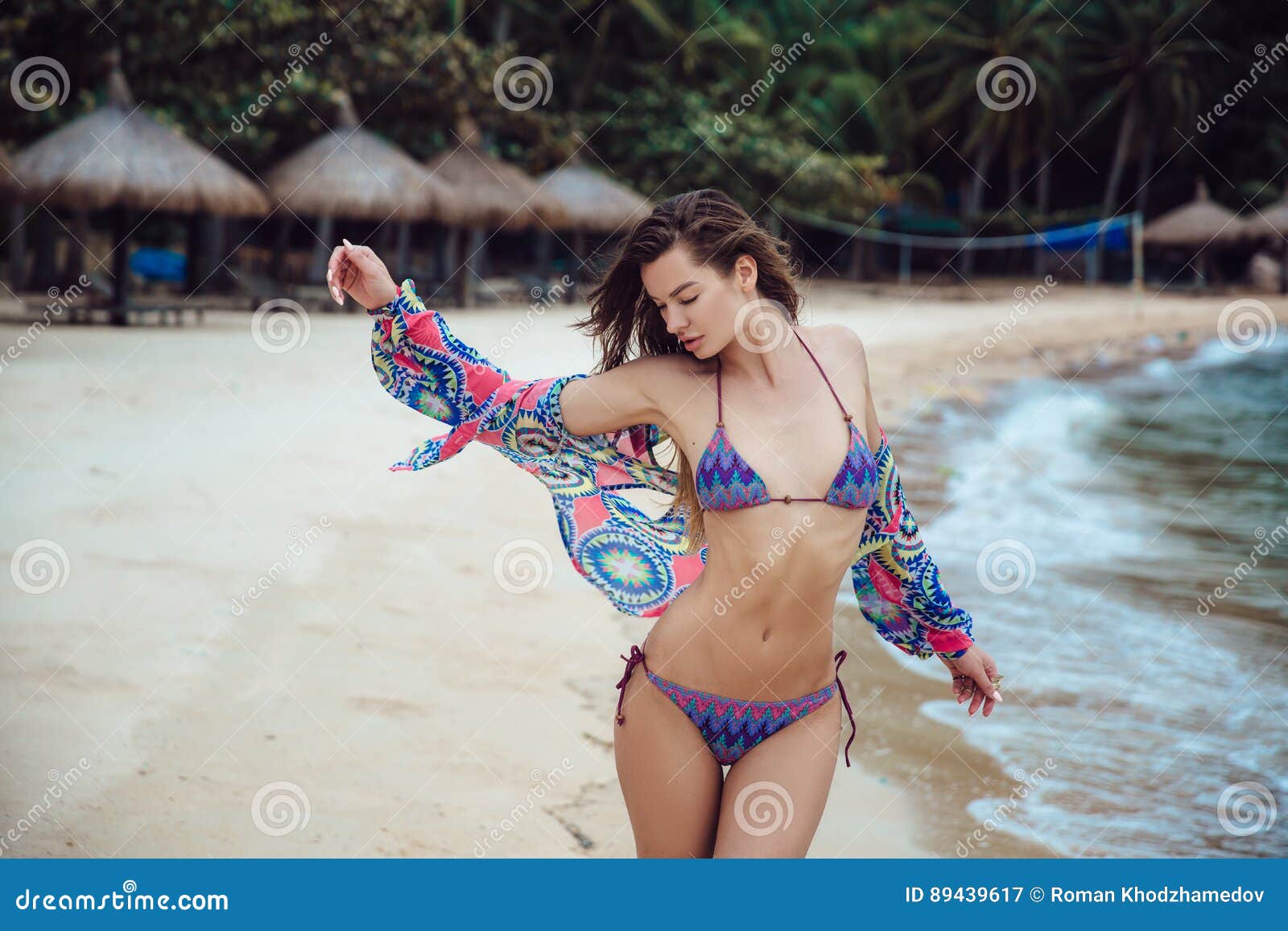 Beautiful Young Brunette Woman in Blue Bikini Posing on the Beach