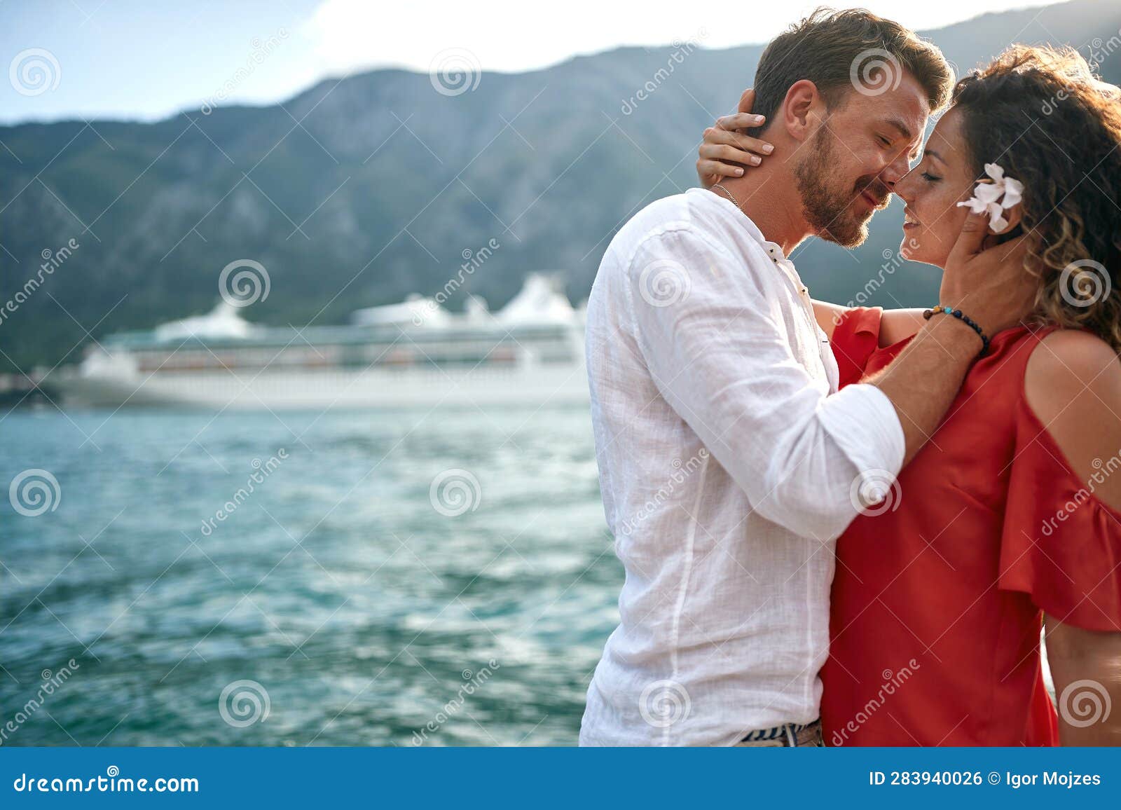 beautiful young couple leaning in for a kiss by water. couple in love. summertime, holiday, love, togetherness concept