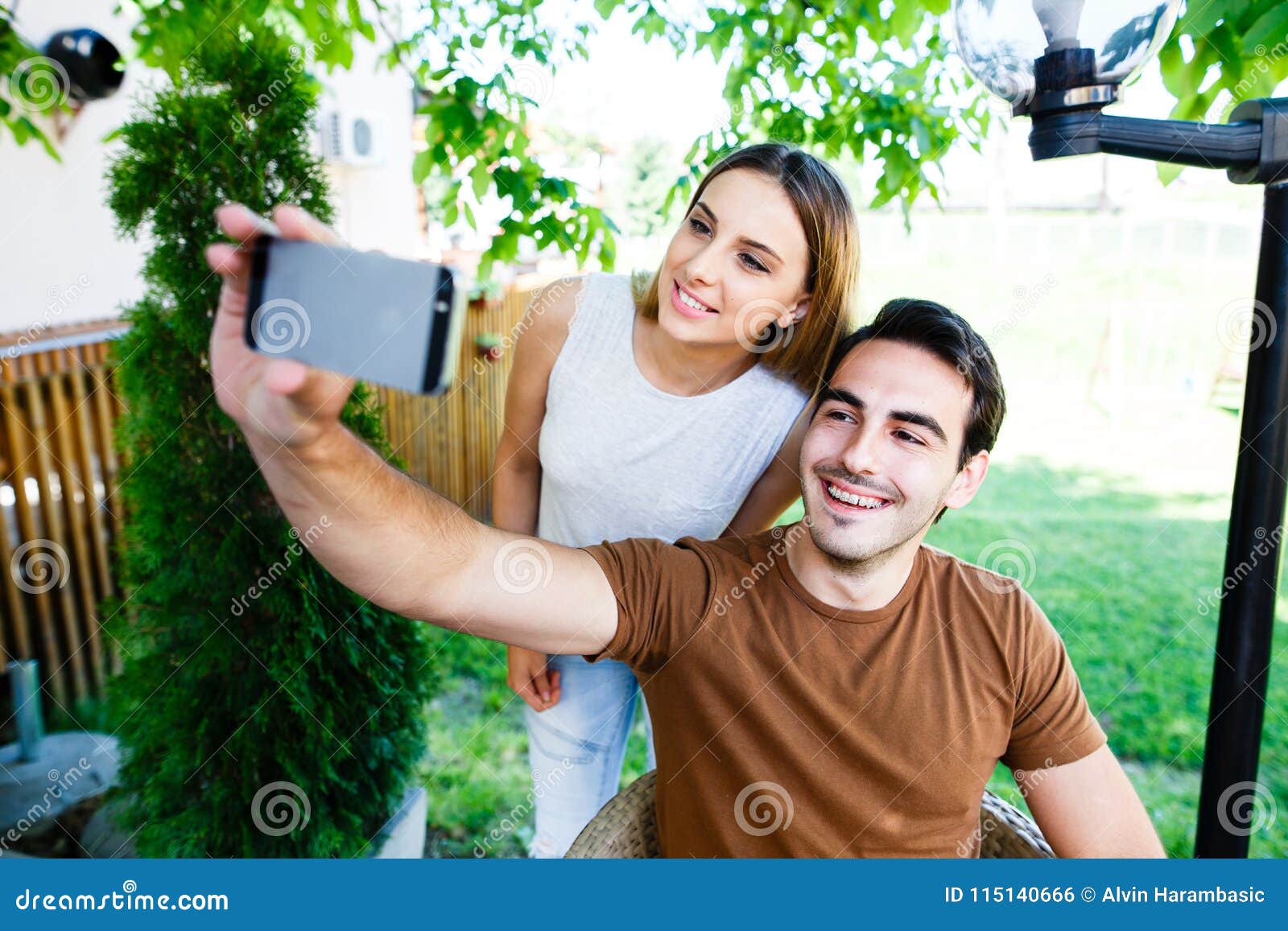 Beautiful Young Couple Taking Selfie While Sitting At Cafe`s Garden