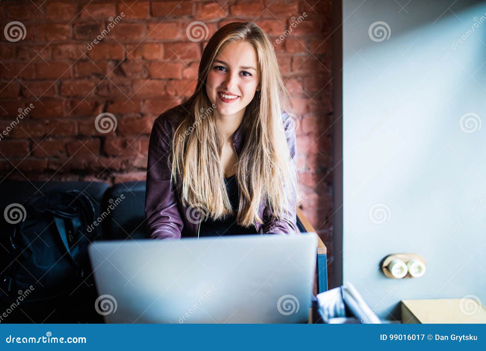 beautiful young freelancer woman using laptop computer sitting at cafe table. happy smiling girl working online or studying and le