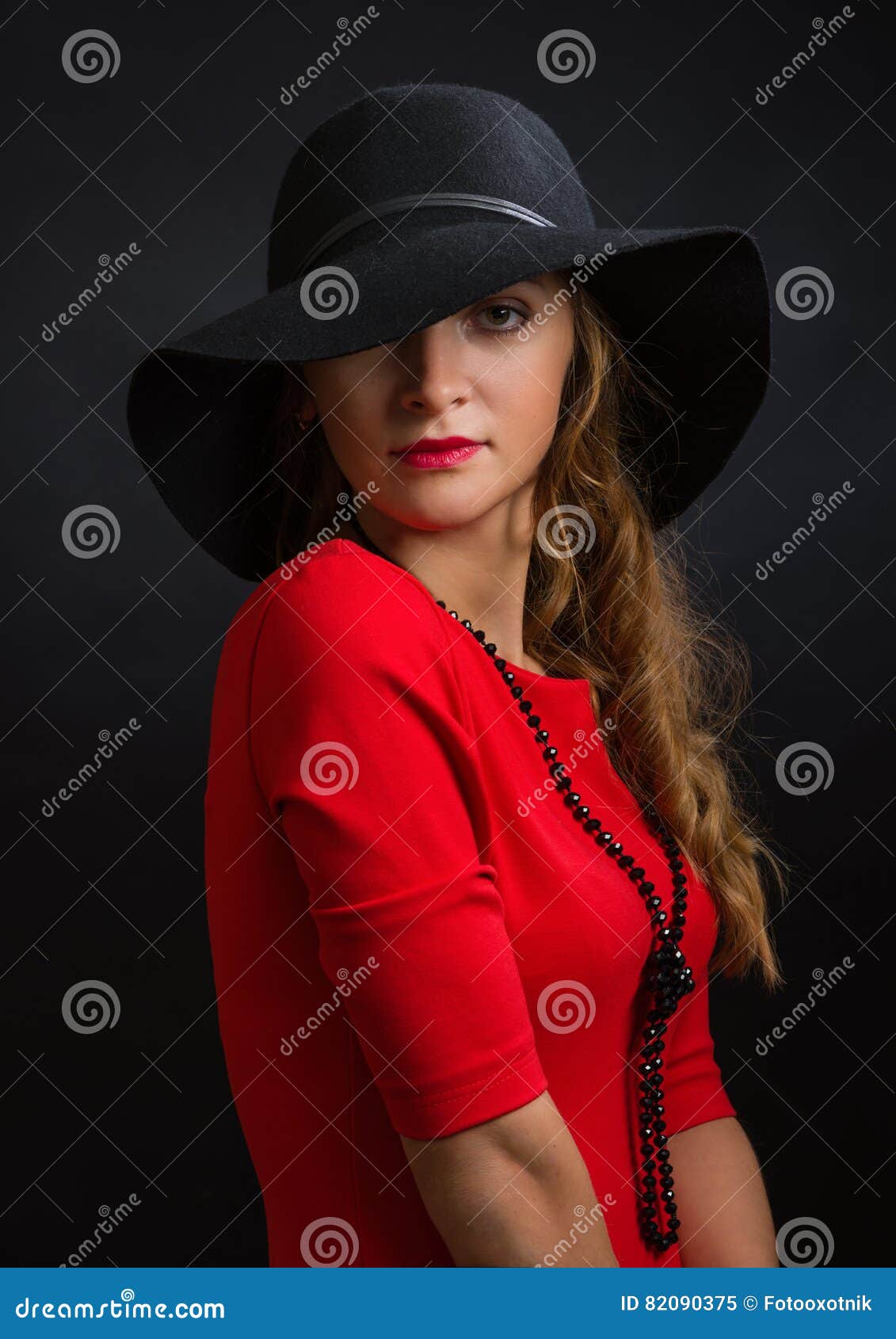 The Beautiful Young Girl in a Bright Red Dress and Black Hat with the ...