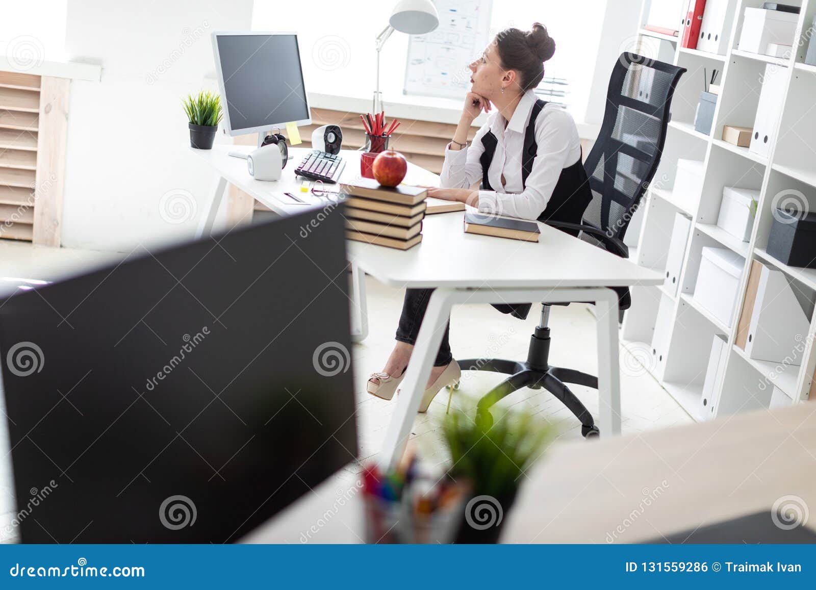 A Young Girl Is Sitting At The Computer Desk In The Office Stock