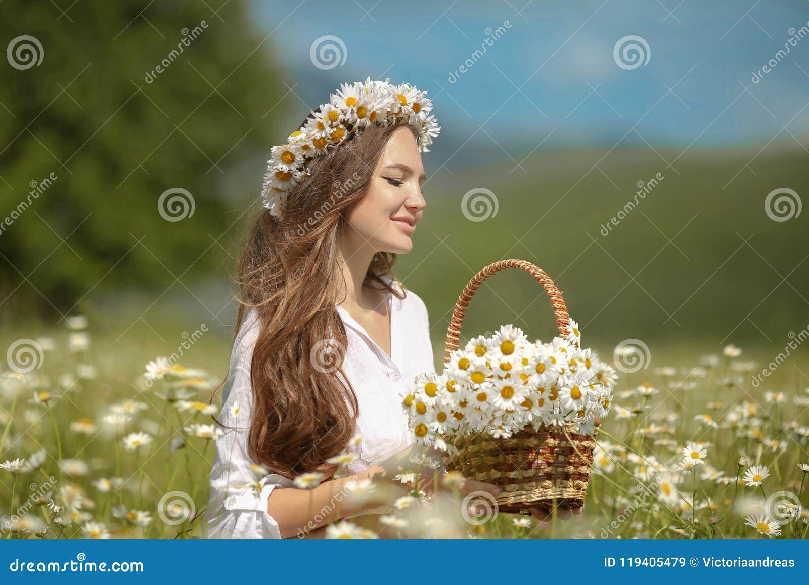 Beautiful young girl in chamomile field. Carefree happy brunette woman with healthy wavy hair having fun outdoor in nature. Daydreaming.