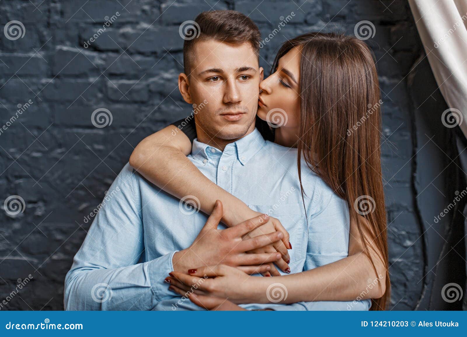 Beautiful Young Girl Kisses a Guy on the Cheek Near a Brick Wall Stock ...