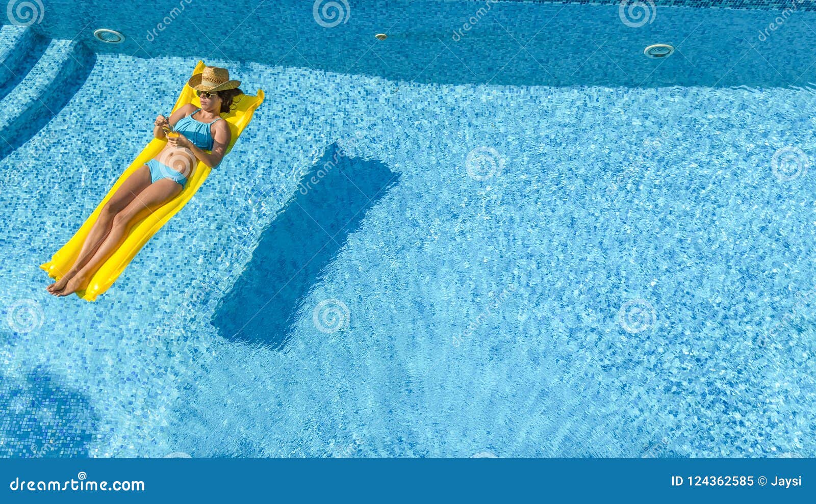 beautiful young girl relaxing in swimming pool, swims on inflatable mattress and has fun in water on family vacation, aerial view