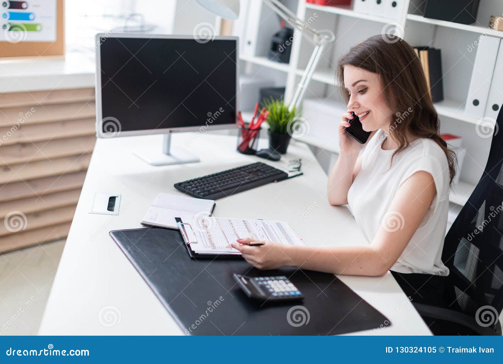 A Young Girl Sitting In The Office At The Computer Desk Talking