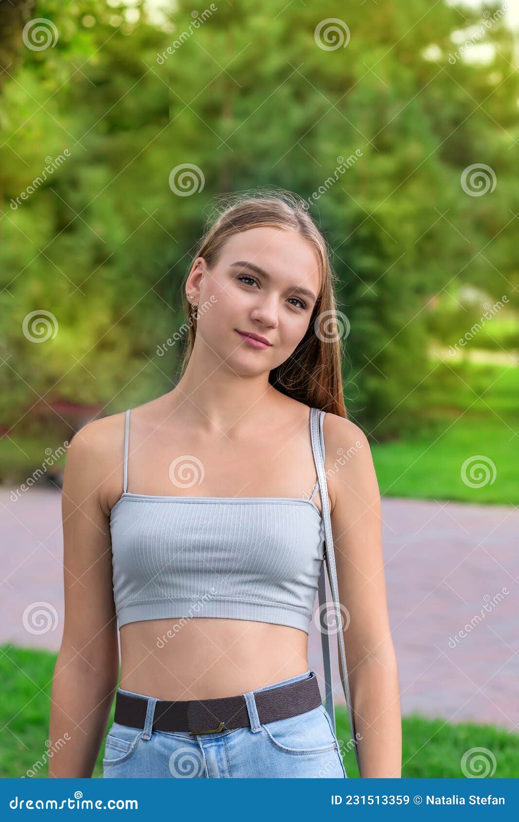 Beautiful Young Girl 16 Years Old, with Long Hair, in a T-shirt and Jeans  Stands Against the Background of a Green Park, Stock Image - Image of  background, brunette: 231513359